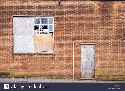 Old Brick Building With Boarded Up And Broken Windows And Door In