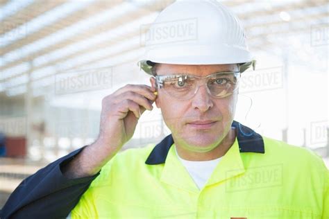 Builder With Safety Glasses Inserting Earplugs On Construction Site