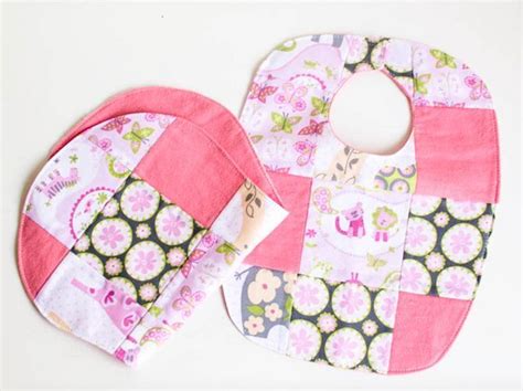 Two Bibs With Pink And Green Designs On Them Sitting Next To Each Other