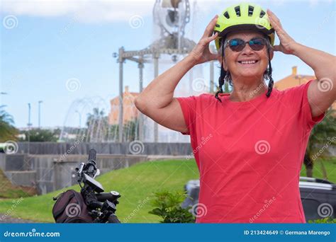 Youthful Senior Woman In Activity With Bicycle In Urban Public Park She Is Wearing A Yellow