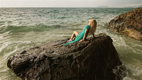 바다 암초 돌 폭풍우 흐린 바다의 바위에 앉아 여자 블루 수영복 드레스 튜닉 컨셉 리조트 해안선 관광 여름 휴일 팔 신체 부분에