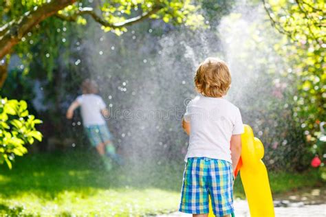 Two Little Kids Playing With Garden Hose In Summer Stock Photo Image