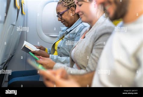 Passengers Reading Book And Using Mobile Smartphones During Airplane