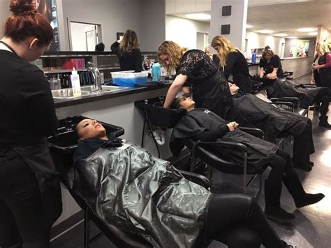 A Group Of Women Getting Their Hair Done In A Salon With One Woman Laying On The Chair