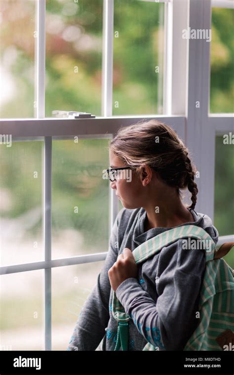 Girl With Backpack Gazing Through House Window Stock Photo Alamy