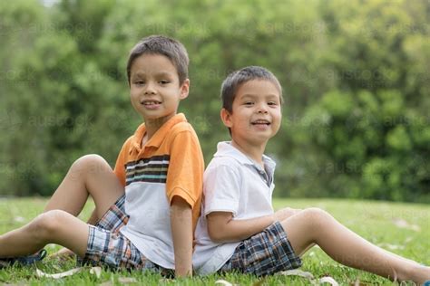 Image Of Brothers Sit Back To Back Outside Austockphoto