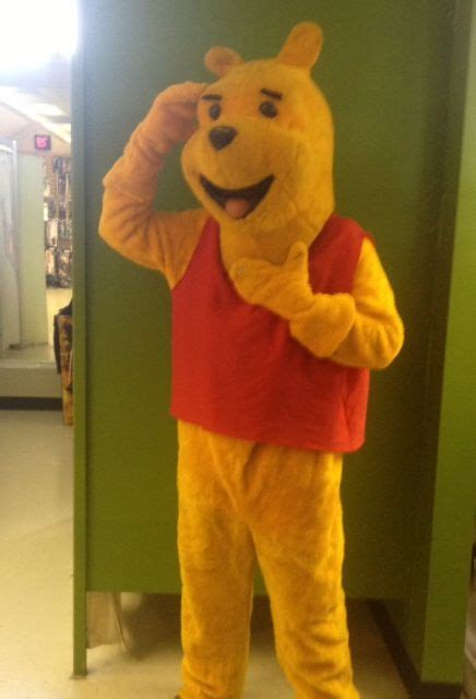 A Man Dressed As Winnie The Pooh Standing In Front Of A Green Wall With