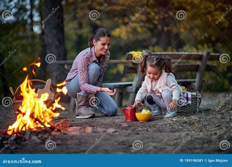 Mother And Daughter Playing Around A Campfire In The Forest Stock Image