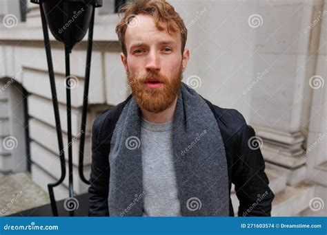 Portrait Of A Brutal Red Haired Man In A Jacket And Scarf On The Street