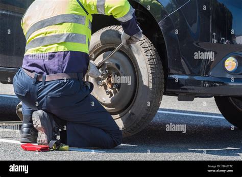 A Mechanic Man Changing Old Wheel Of A Car On The Road For Assistance Stock Photo Alamy