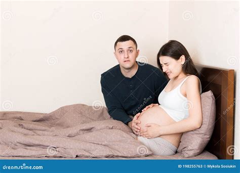 Husband Shocked While His Pregnant Wife Has Contractions On Bed In Home Stock Image Image Of