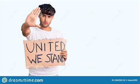 Young Hispanic Man Holding United We Stand Banner With Open Hand Doing