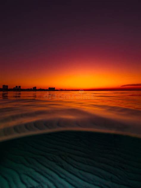 Split View With Colorful Sunset And Underwater Sandy Sea Bottom Stock