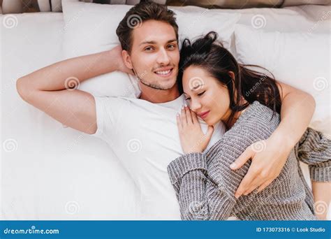 Smiling Man Posing In Bed With Wife Sleeping On His Chest Indoor Overhead Photo Of Chilling