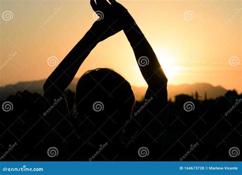 Silhouette Of Woman Raising Arms Towards The Sunset Stock Photo Image