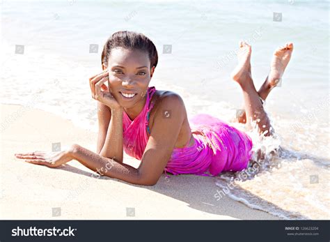 Attractive Black Woman Laying Down On The Sea Shore With The Waves