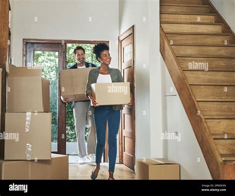 Interracial Couple Moving Into A New Modern House Carrying Boxes And Arriving Home Together