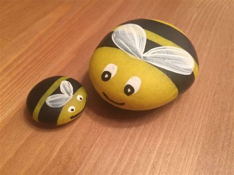 Two Painted Rocks Sitting On Top Of A Wooden Table