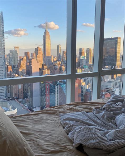 An Unmade Bed In Front Of A Large Window Overlooking The Cityscape And