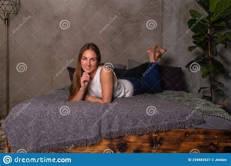 Smiling Woman Lying On Her Stomach In Bed Stock Image Image Of Jeans Girl 259883527
