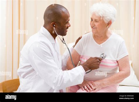 Doctor Giving Checkup With Stethoscope To Woman In Exam Room Smi Stock