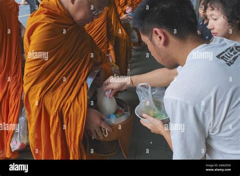 A Buddhist Layman Places Alms In A Buddhist Monks Alms Bowl In Bangkok