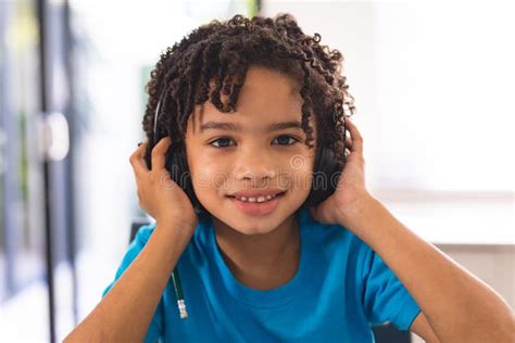 Portrait Of Smiling Hispanic Cute Boy Wearing Headphones At Home Stock