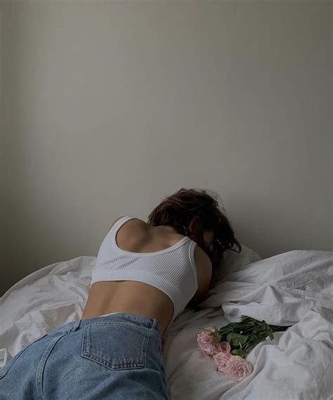 A Woman Laying On Top Of A Bed Next To Flowers
