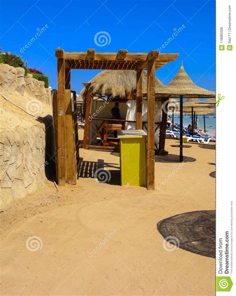 A Row Of Straw Umbrellas To Protect Against Overheating And Sunbeds On A Sandy Beach Against A