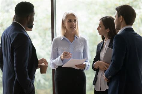 Multiethnic Young Employees Listen Guidance Of Middle Aged Female Boss