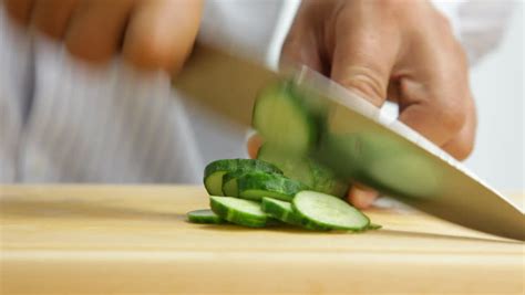 Man Cutting Cucumbers On The Wooden Board Stock Footage
