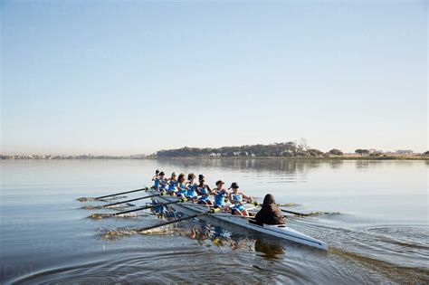 Female Rowing Team Rowing Scull On Tranquil Lake Stock Photo