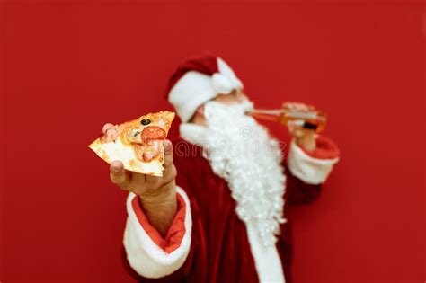 Piece Of Delicious Pizza In Hand In Santa Claus Stands On A Red