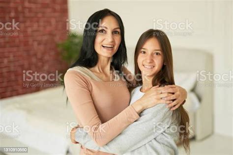 Loving Latin Mother And Daughter Hugging Each Other Smiling At Camera