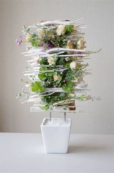 A White Vase Filled With Lots Of Flowers Sitting On Top Of A Table Next