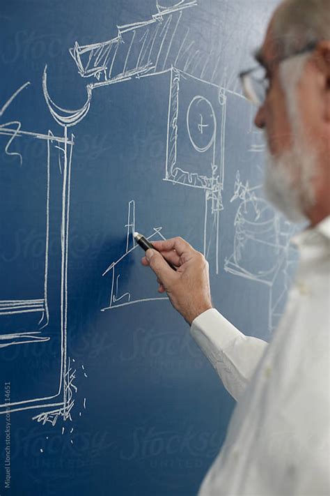 Mature Professor Drawing On A Blue Blackboard With Chalk By Miquel