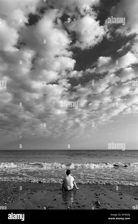 A Young Boy Sitting Alone On A Beach Stock Photo Alamy