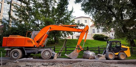 Excavator Parked On Sidewalk Opposite Small Mini Bulldozer