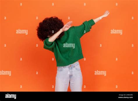 woman with afro hairstyle wearing green sweater showing dab dance popular internet meme pose