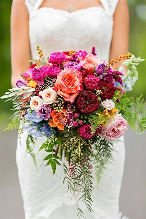 A Bridal Holding A Bouquet Of Flowers And Greenery