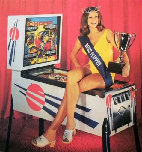 A Woman Sitting On Top Of A Pinball Machine With A Trophy In Her Hand