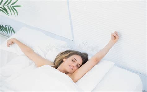 Lovely Woman Stretching Out Lying Under The Cover On Her Bed Stock