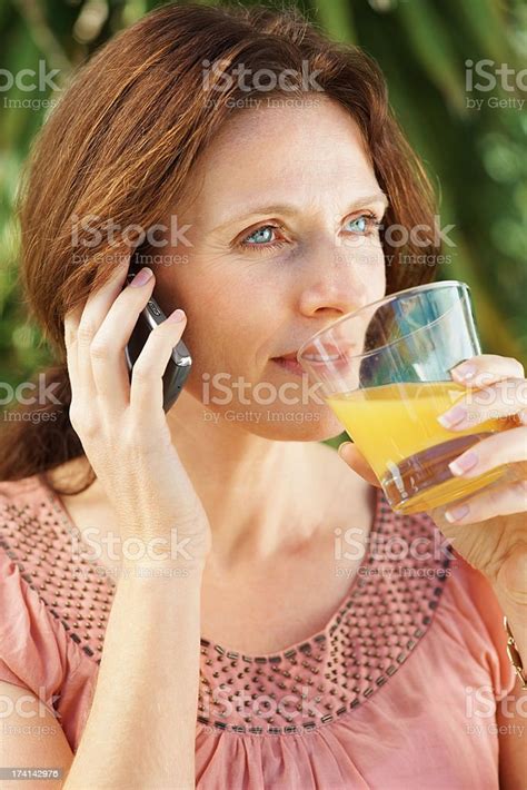 Beautiful Mature Woman With Juice Glass Talking On The Phone Stock