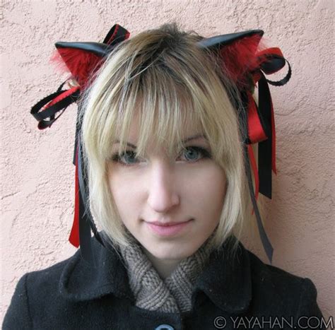 A Woman With Blonde Hair Wearing A Black Coat And Red Cat Ears On Her Head