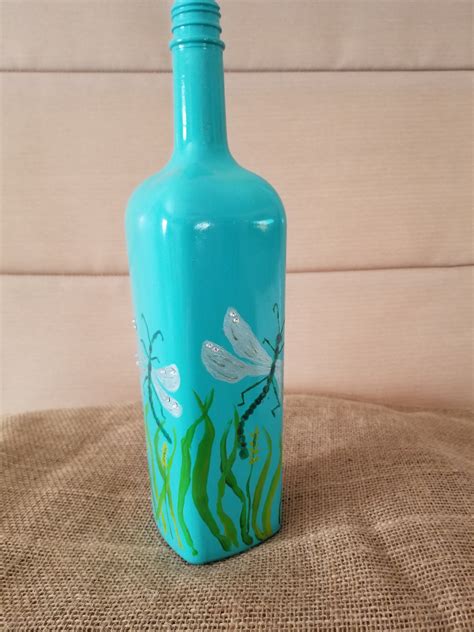 A Blue Glass Bottle With Dragonflies Painted On It