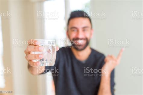 잘 생긴 히스패닉 남자 마시는 신선한 유리 의 물 매우 행복 가리키는 와 손과 손가락 으로 측면 가리키기에 대한 스톡 사진 및 기타 이미지 Istock