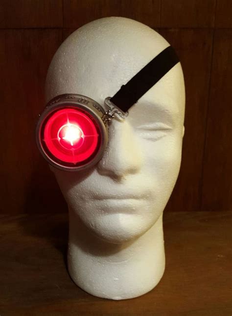A White Mannequin Head With A Red Light In Its Eyepiece