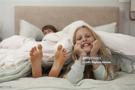 Portrait Of Girl Lying On Bed With Mothers Feet Bildbanksbilder Getty