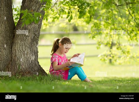 Younge Girl Reading A Book Under A Tree In Northern Alberta Canada