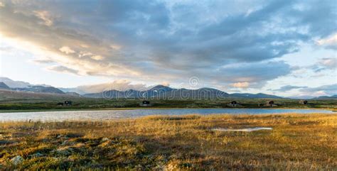 Golden Hour In Mountain Scenery With Cabins And Lake Stock Photo